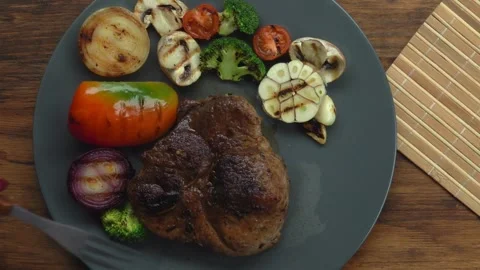 Top view fork pierces juicy steak meat knife cuts off a piece Stock Footage 234137315