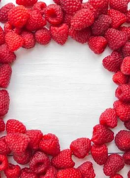 A top view frame of fresh red raspberries arranged on a white wooden backgr.. Stock Photos