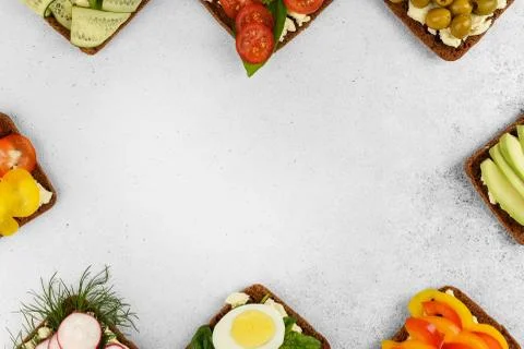 Top view frame open faced vegetarian sandwiches on stone background. Stock Photos