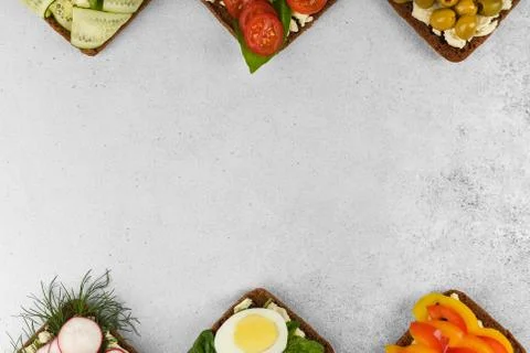 Top view frame open faced vegetarian sandwiches on stone background. Stock Photos