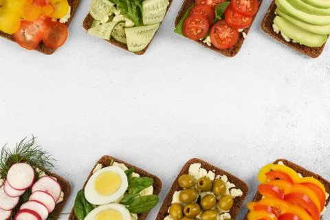 Top view frame open faced vegetarian sandwiches on stone background. Stock Photos