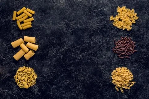 Top view of frame of various raw pasta on black concrete table 库存照片