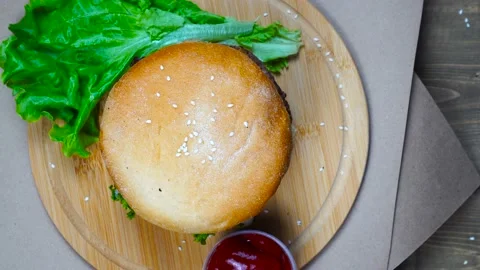 Top view of fresh appetizing hamburger rotating on wooden plate Stock Footage 112022461