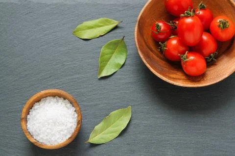 Top view: fresh cherry tomatoes, salt and bay leaves on a black background wi Foto stock