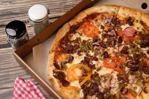 Top view of a fresh cooked pizza in a cardboard box , pizza knife on a napkin Stock Photos