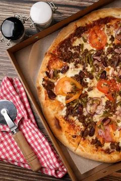 Top view of a fresh cooked pizza in a cardboard box , pizza knife on a napkin Stock Photos