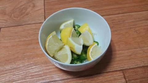 Top view of fresh lemon slices in a bowl over a wooden floor. Fruit backgroun Stock Photos