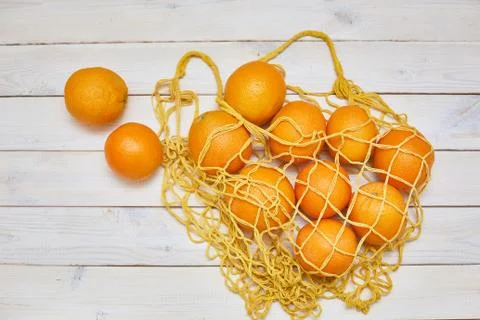 Top view of fresh oranges in string bag over white rustic background. Stock Photos