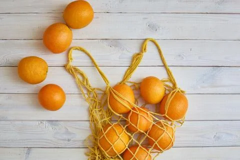 Top view of fresh oranges in string bag over white rustic background. Stock Photos