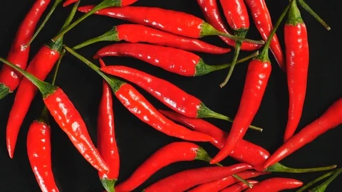 Top View Of Fresh Raw Red Chili Peppers Rotating On A Black Plate. Video stock 127512816