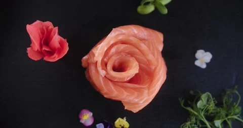 Top view fresh salmon in the shape of rose on plate, ginger and flowers around Stock Footage 148765942