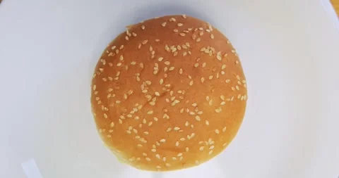 Top view of a fresh sesame burger bun rotating on a white plate 스톡 동영상 337998036