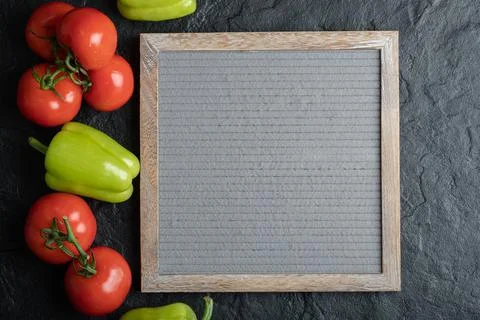 Top view of fresh vegetables with board over black background Stock Photos
