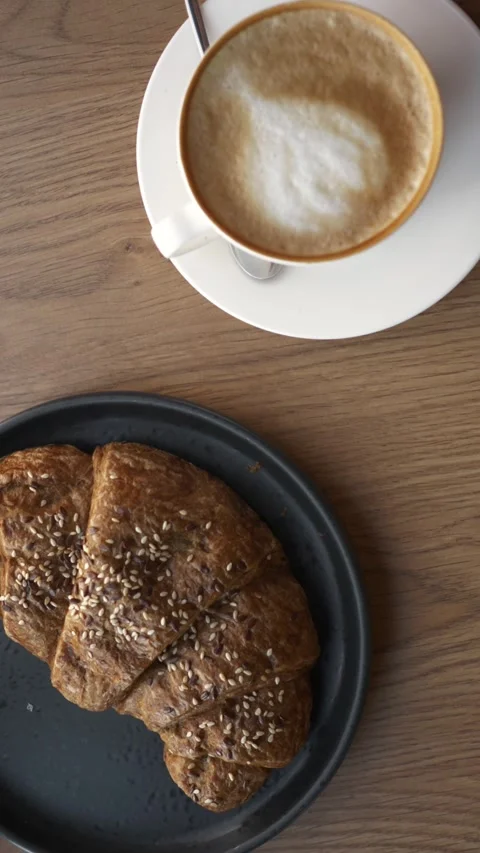 Top view of fresh whole grain seed croissant and cappuccino coffee Stock Footage 342852097