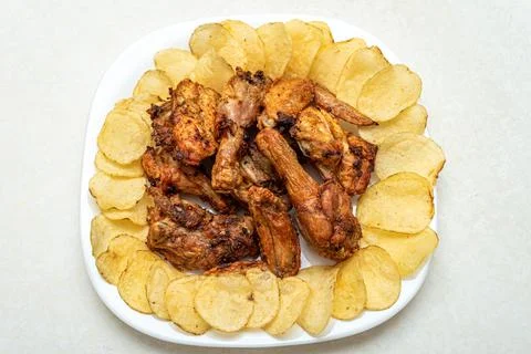 Top view of freshly cooked crispy grilled chicken pieces with potato chips on a Stock Photos