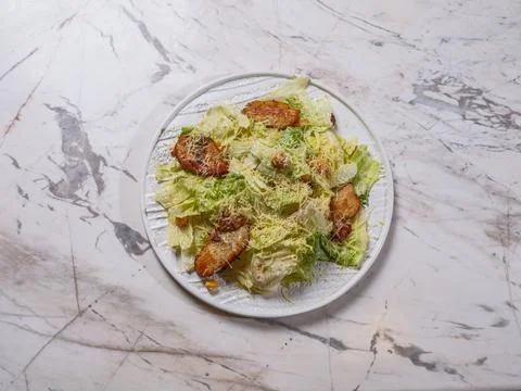 Top view of a freshly made Caesar salad with grilled chicken on marble. 스톡 사진