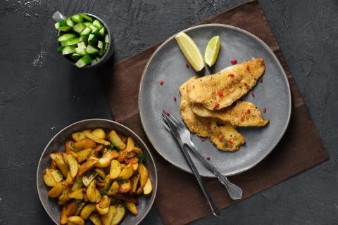 Top view of fried breaded hake fillet with spice and roasted potato wedges Foto stock
