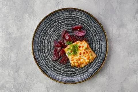 Top view of fried cod fillet with melted cheese topping and roasted beetroot  Stock Photos