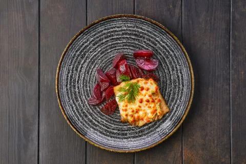 Top view of fried cod fillet with melted cheese topping and roasted beetroot  Stock Photos