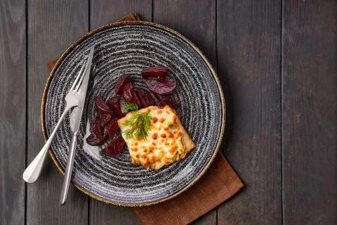 Top view of fried cod fillet with melted cheese topping and roasted beetroot  Stock Photos