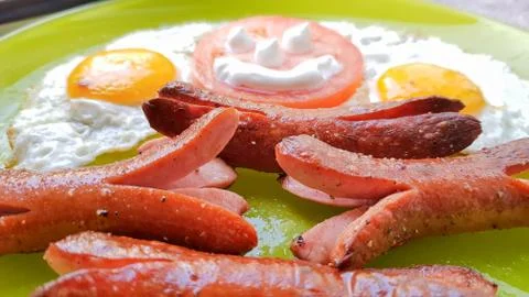 Top view of fried egg and sausages on a green plate, serving breakfast for th Stock-Fotos