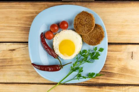 Top view of a fried egg, two chilli toast and cherry tomatoes on a blue plate Stock Photos