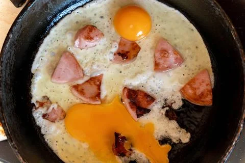 Top view of fried eggs and sausage slices in a frying pan Foto stock