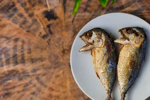 Top view fried mackerel on a white plate with real wooden table with copy spa Stock Photos