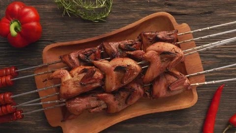 Top view of fried quails on the skewers on the wooden plate placed on the table Stock Footage 220143275