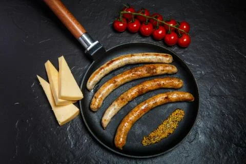 Top view on fried thin sausages and mustard on frying pan Фото