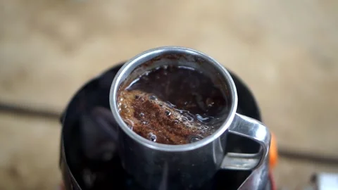 Top view of frothy coffee being cooked in a metal mug on a portable gas stove Stock Footage 336070419