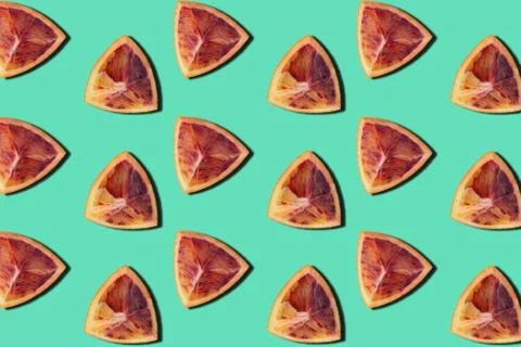 Top view fruit art pattern of red orange slices on green background Stock Photos