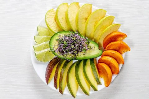 Top view fruit slicing on a white plate with avocado and micro green cabbag.. Stock Photos