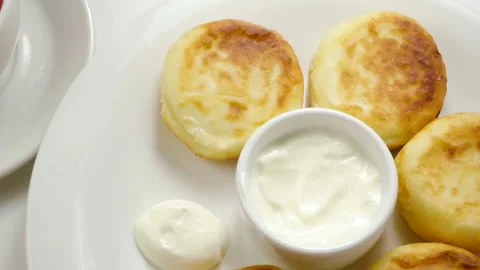 Top view of fruit tea is being poured into cup. Cheesecakes on plate. Slow mo HD Stock Footage 107435062