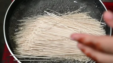 Top view on fry-pen of boiling water on kitchen stove. Female chef adds auth Stock Footage 203477275