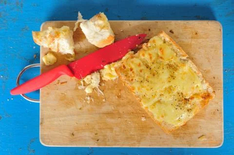 Top view garlic bread with red knife on the chopping block. Stock Photos