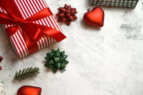 Top view on gift box in red paper with bows and ornaments near on concrete ba Stock Photos