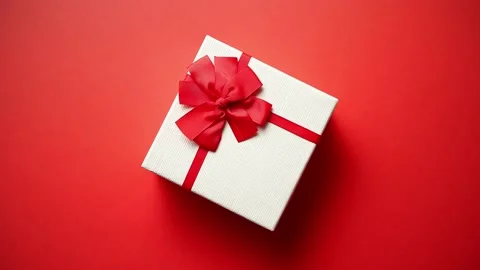 Top view on gift wrapped in striped gift paper decorated with ribbon on red Stock Footage 228606366