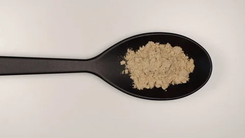 TOP VIEW: Ginger powder fill a black plastic spoon on a table - Stop motion Stock Footage 124623089