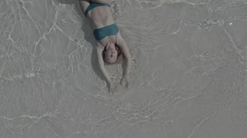 Top view of a girl lying on the beach and being washed by the waves of the sea. Stock Footage 242349869