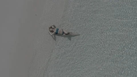 Top view of a girl lying on the beach and being washed by the waves of the sea. Stock Footage 242354548