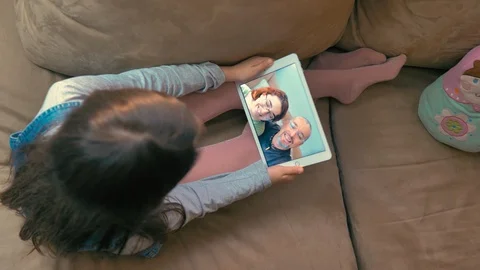 Top view of girl on sofa talking to family on tablet in video conference Stock Footage 128671794