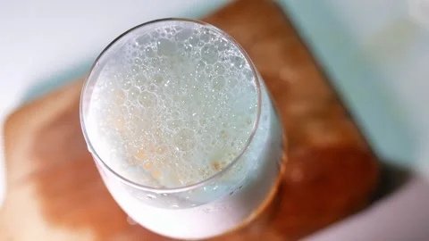 Top view: a glass of beer on a table. Bubbles burst in the foam of the beer Stock Footage 346187137