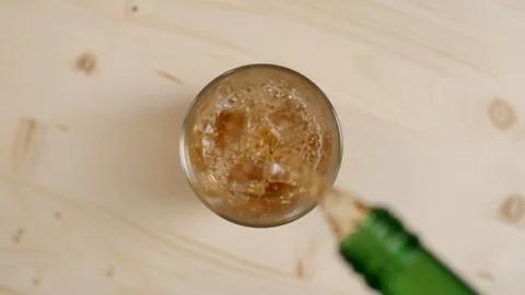Top view glass ice cubes on wooden table, alcoholic drink pouring from bottle Stock Footage 107713148