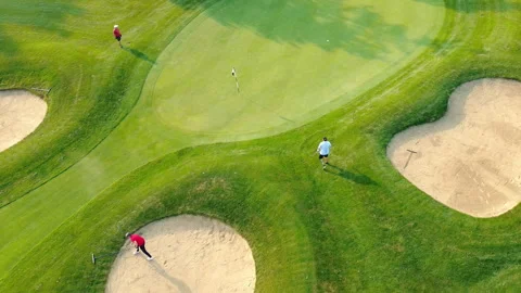 Top view of a golf course on a sunny day with golfers on the course. Three Stock Footage 256039804