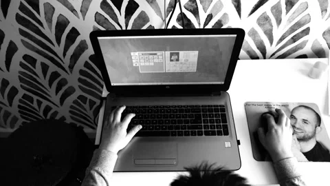 Top view grayscale shot of a child playing Minecraft on a laptop behind a desk a Stock Footage 236932175