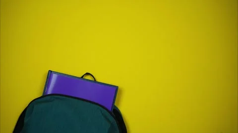 Top view of green backpack with school supplies emerging from school bag Video stock 244600507