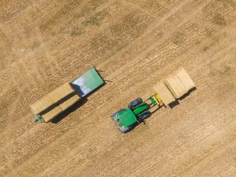Top view of green tractor loading straw bales on a trailer. Stock Photos