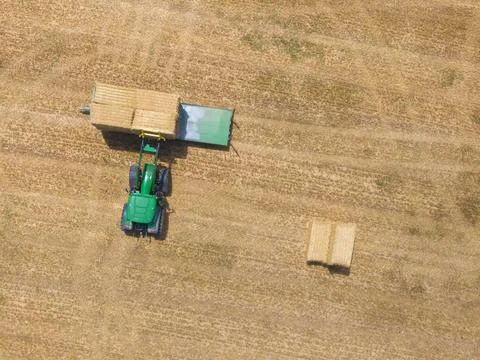 Top view of green tractor loading straw bales on a trailer. Stock Photos