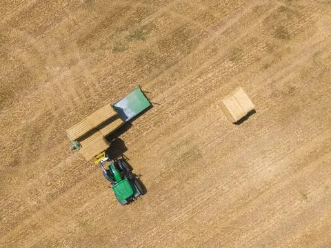 Top view of green tractor loading straw bales on a trailer. Stock Photos